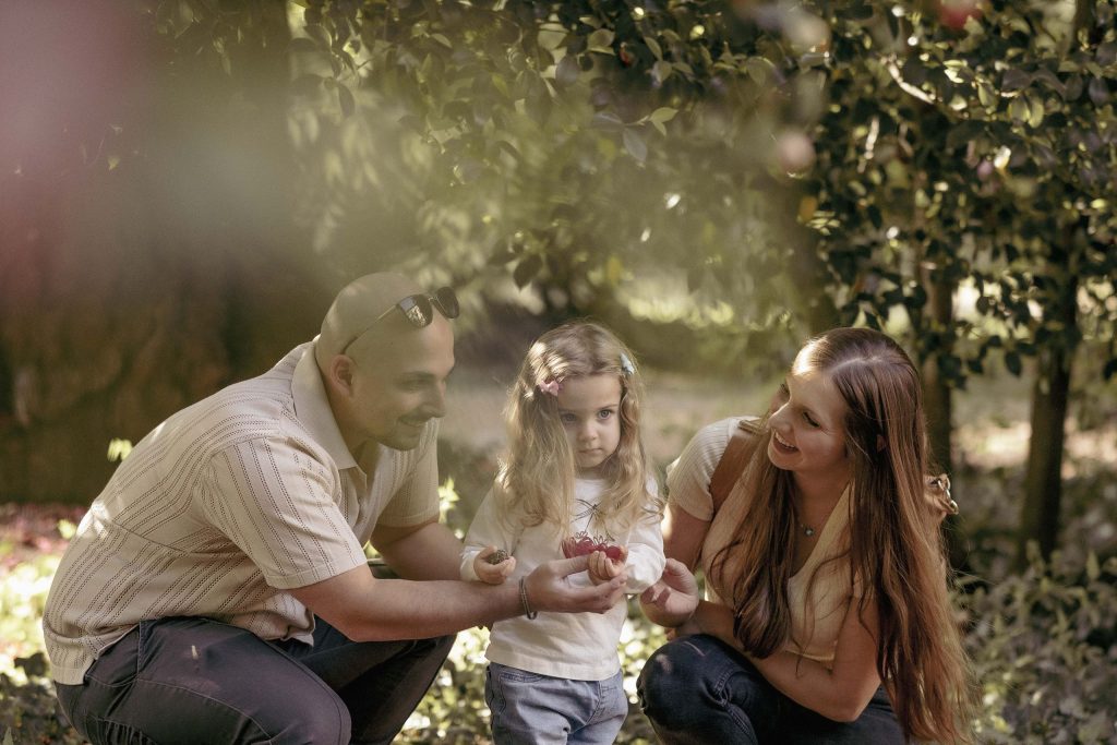 A mother and father smile at their little girl in Villa dei Cedri Park in Bellinzona