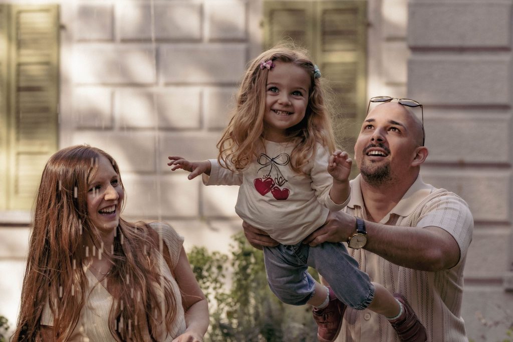 A father lifts his little girl high in the air by a fountain in Villa dei Cedri Park in Bellinzona