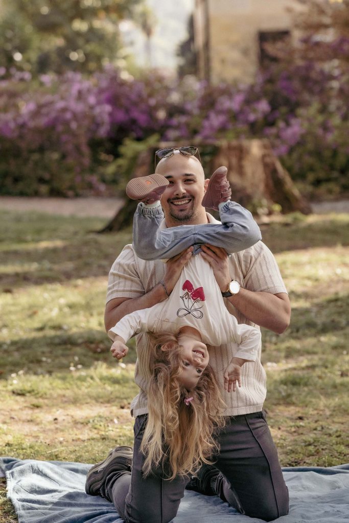 A father is laughing and playing with his little girl in Villa dei Cedri Park in Bellinzona