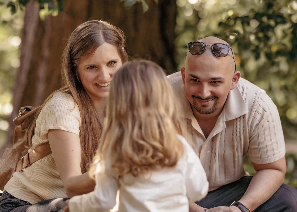 A mother and father smile at their little girl in Villa dei Cedri Park in Bellinzona