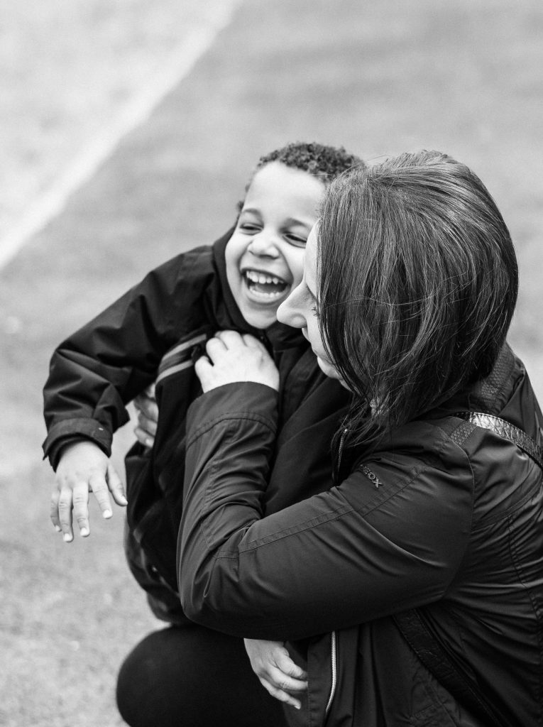 A mother and her young son cuddle up together, laughing, in London