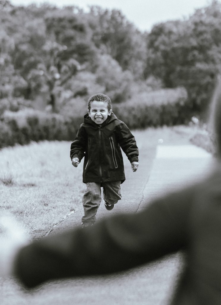A little boy runs laughing into his mother's arms in London