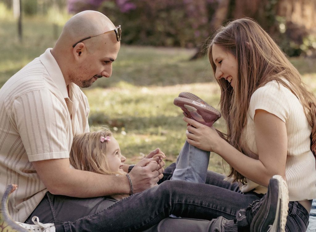 A father and a mother are playing with their little girl in Villa dei Cedri Park in Bellinzona