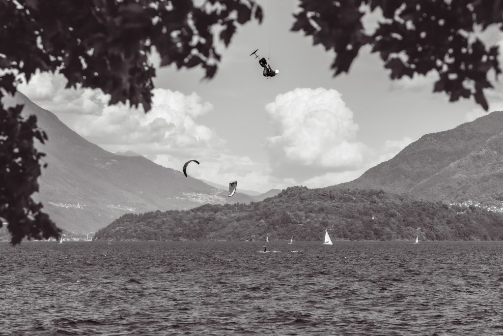 A man is kitesurfing on Lago di Como in Italy, jumping high into the air