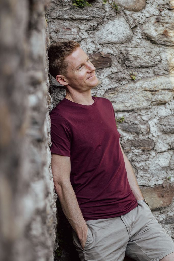 A man leans against the wall, smiling at Castel Grande in Bellinzona