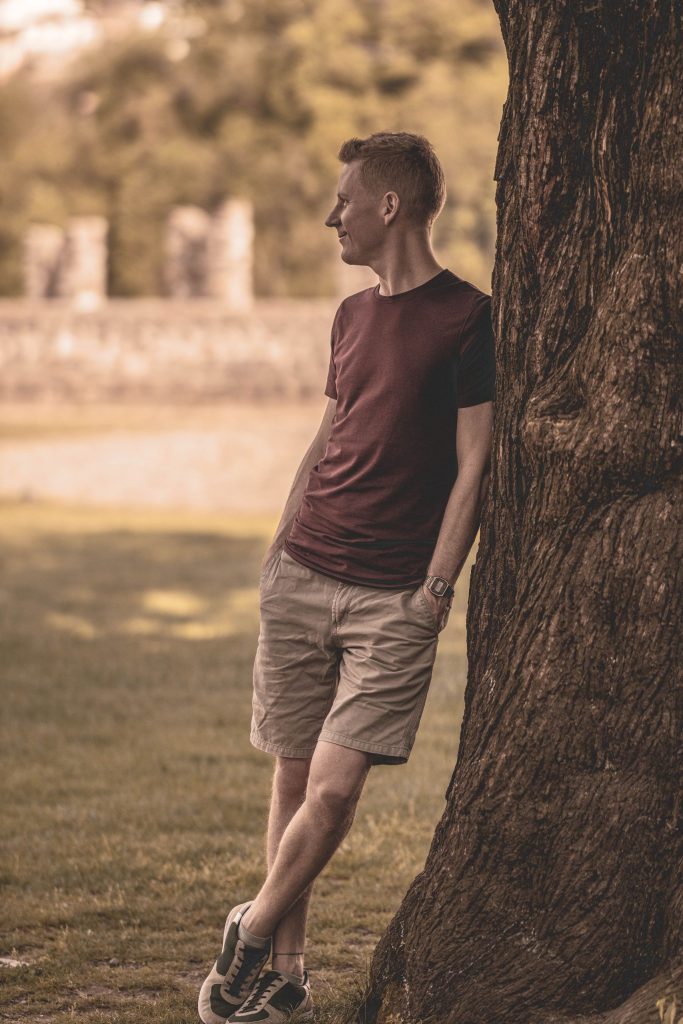 A man poses at Castel Grande, leaning against a tree in Bellinzona