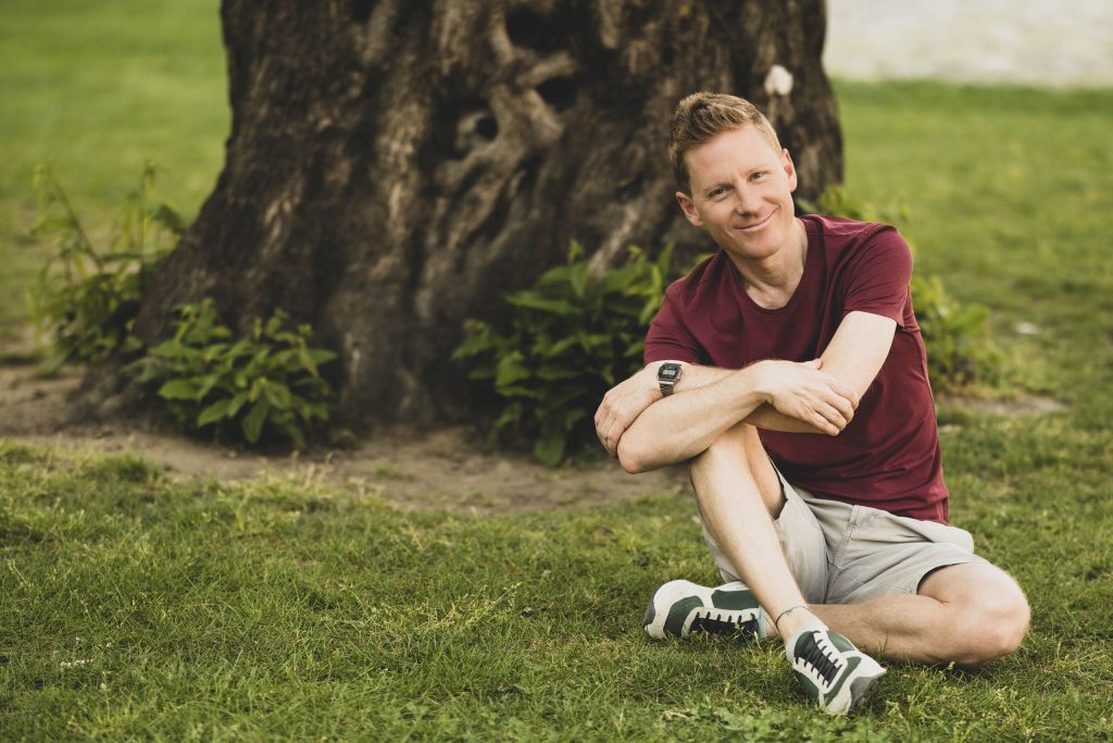 A man poses at Castel Grande, sitting on the grass in Bellinzona