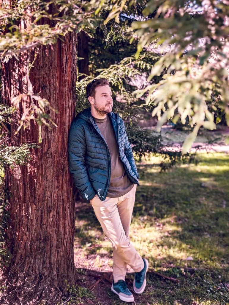 A man is leaning against a tree in Villa dei Cedri Park in Bellinzona