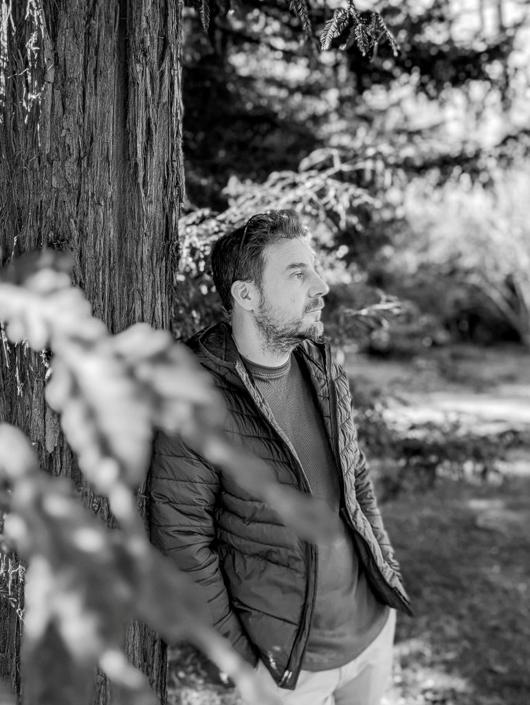 A man is leaning against a tree in Villa dei Cedri Park in Bellinzona